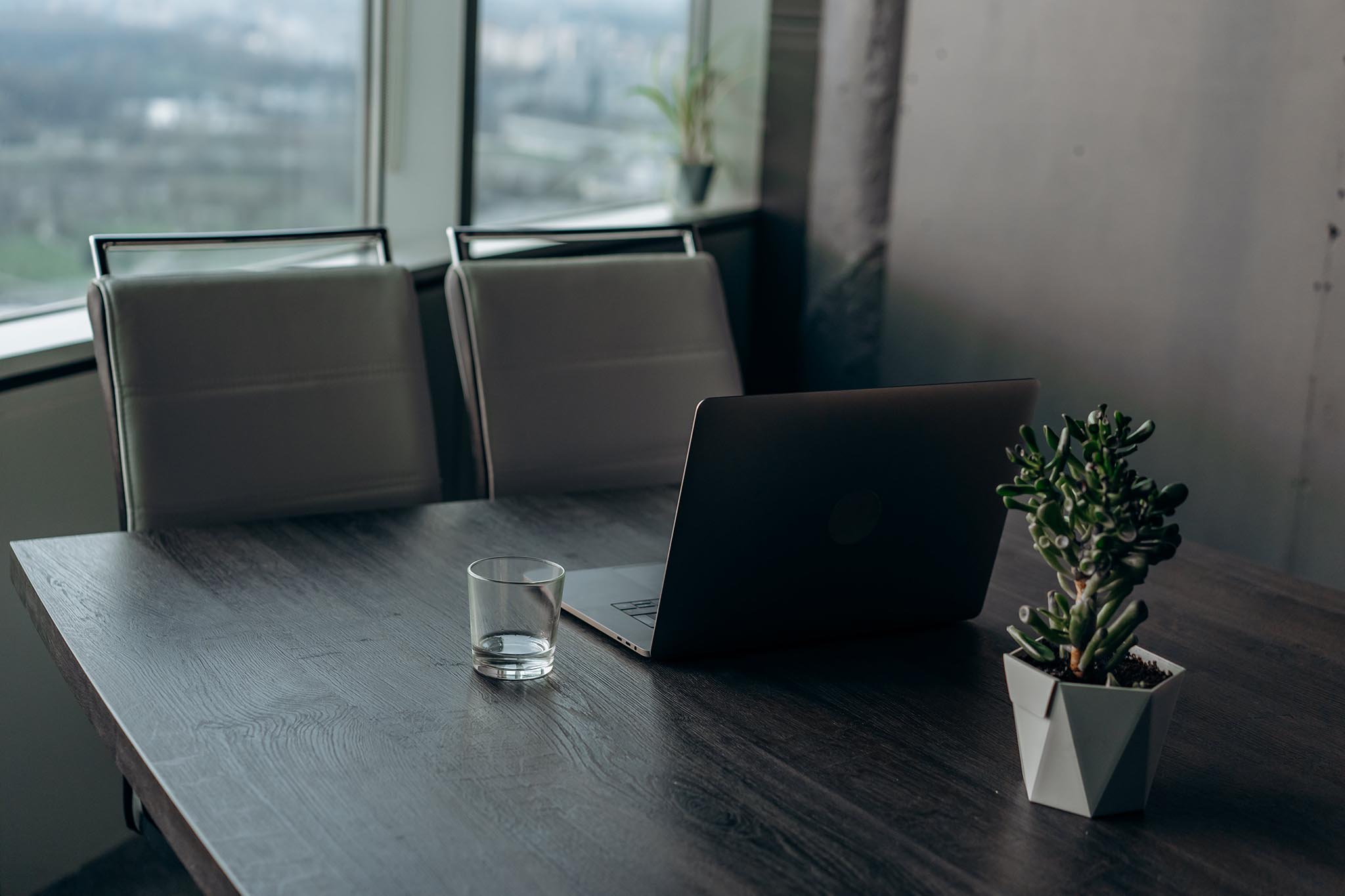 Older man in glasses sitting with laptop on coffee table, smiling while working.